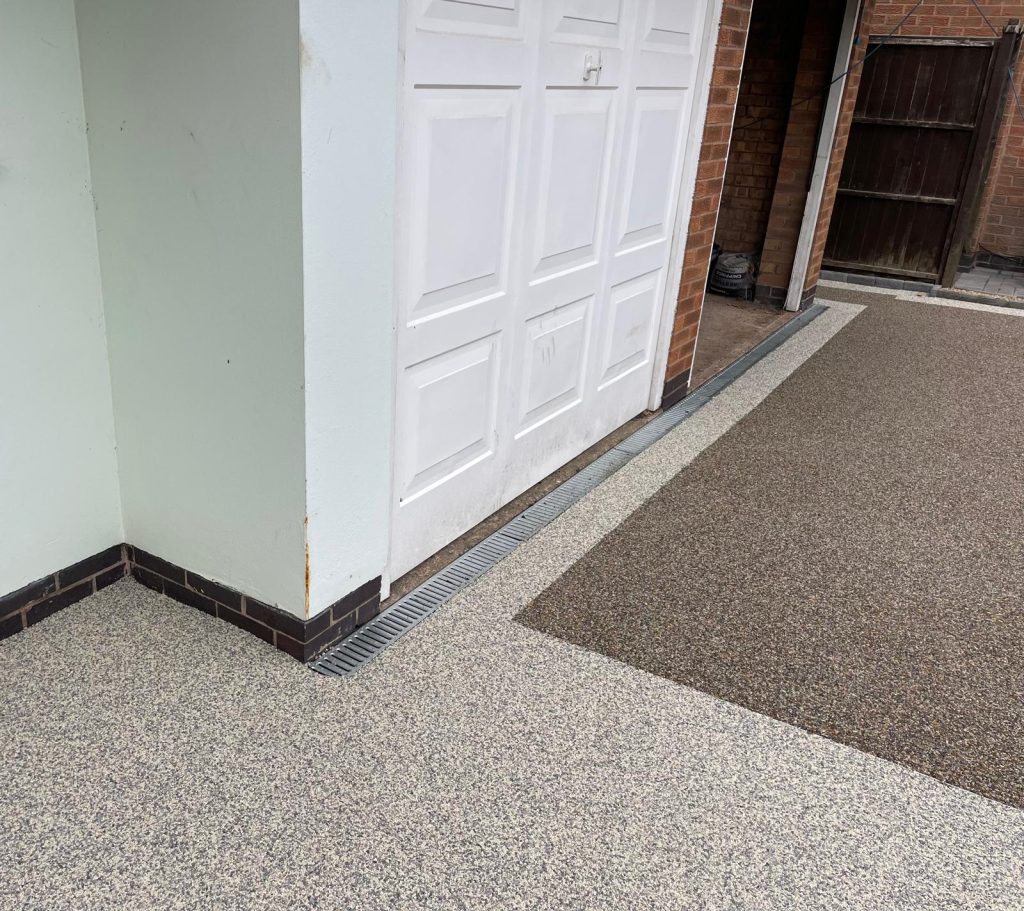 Contrasting staffordshire pink and winter resin colours installed to a resin driveway in Leicester. Featuring ACO drainage to front entrance of garage.